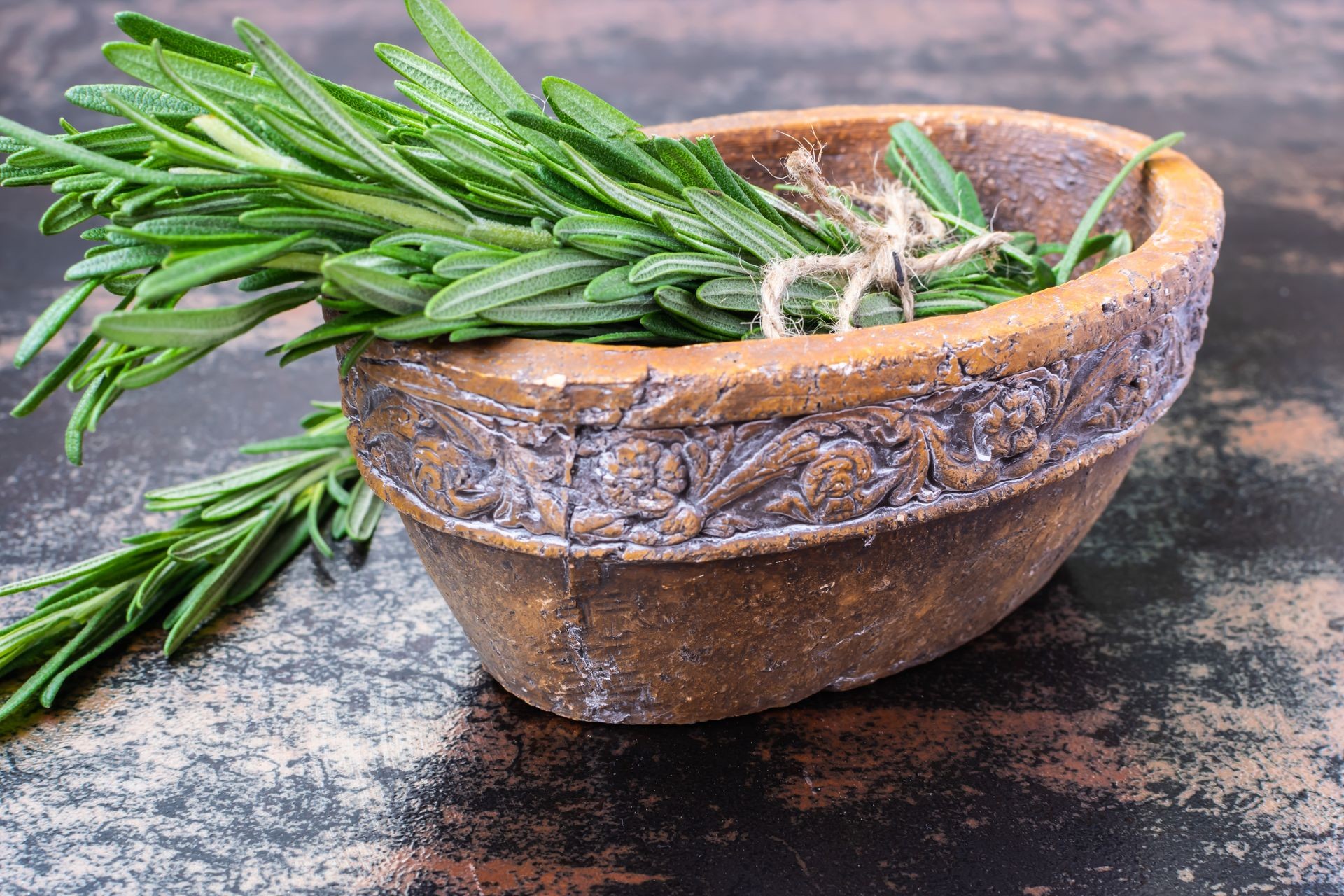 Fresh rosemary herb isolated in vintage clay bowl on dark rustic background. Fresh rosemary herb isolated in vintage clay bowl on dark rustic background.